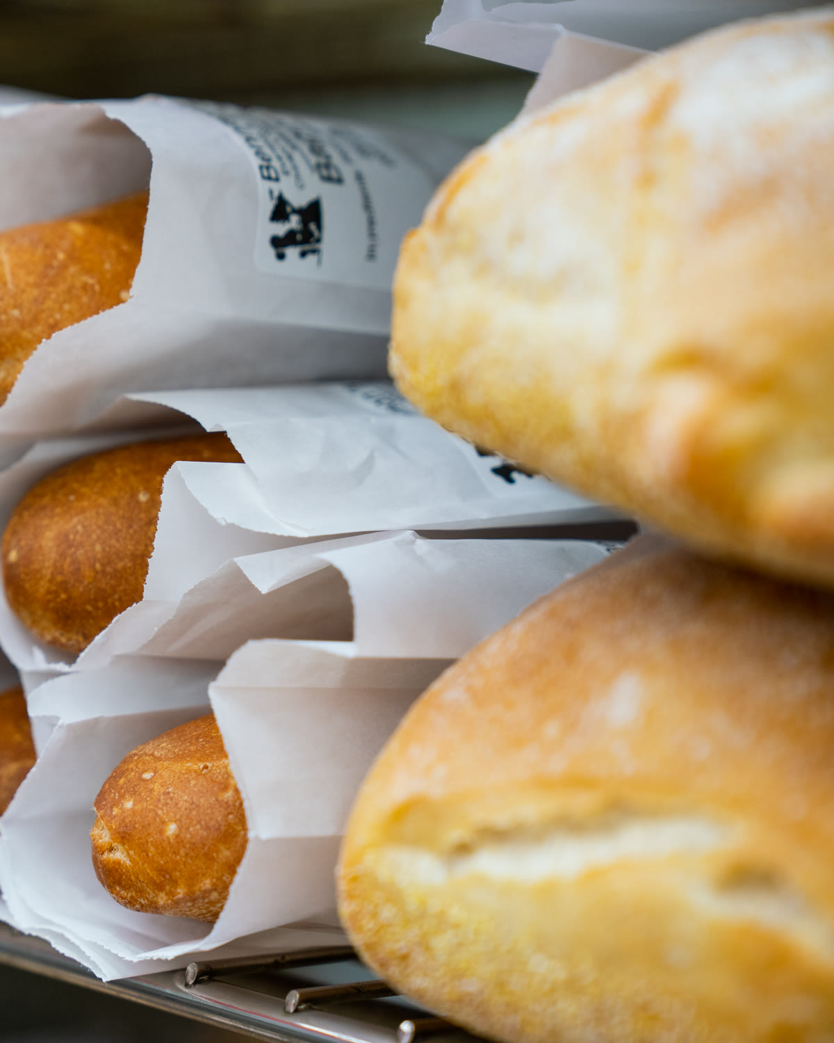 Fresh loaves and baguettes in white paper bags on the bread shelf